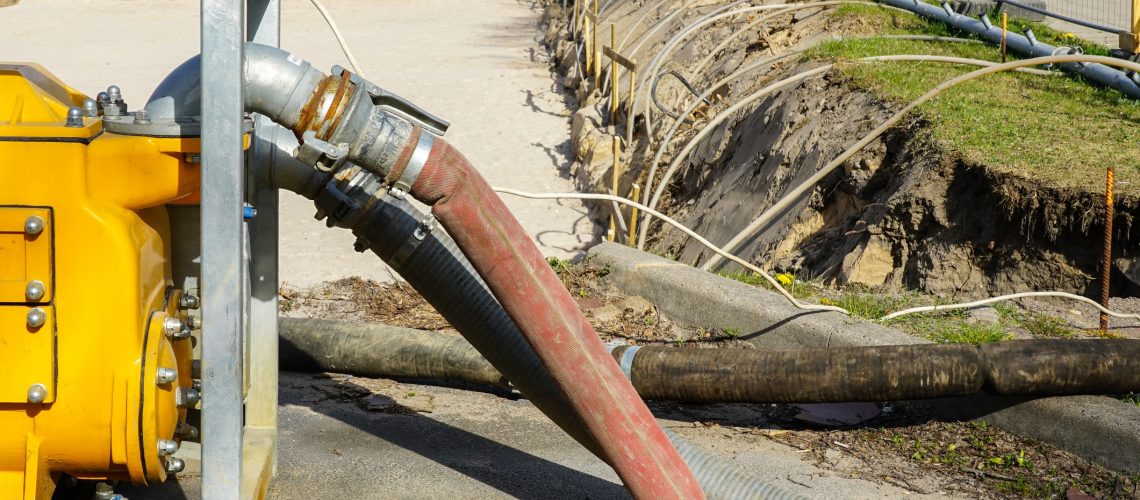 Large yellow portable electric water pump with hose for dewatering the deep pit of the building foundation